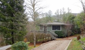 A small, single-story house with a covered porch and a staircase leading to the front door.