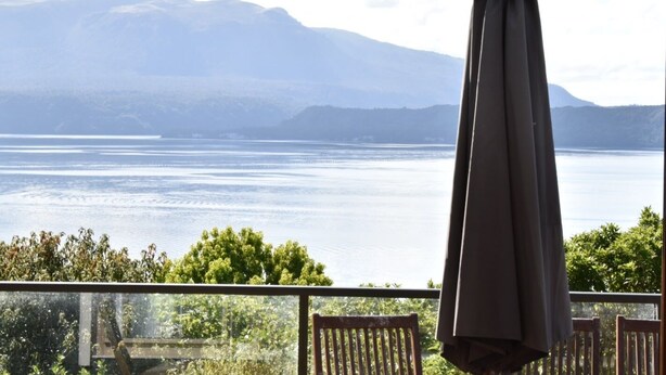 A balcony with a view of a calm lake and distant mountains. - Holiday home at Lake Tarawera, Rotorua (Lake Tarawera)