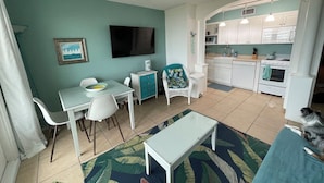 A compact living space with a dining area, a sofa, a television, and a kitchen. - One Bedroom Oceanfront Condo With Room for Six (South Padre Island)