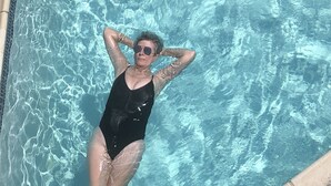 A person in a black swimsuit floating in a clear blue pool. - One Bedroom Oceanfront Condo With Room for Six (South Padre Island)