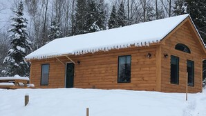 A wooden cabin with a snow-covered roof and windows, surrounded by trees. - Serene Country Cabins 2 In the heart of Vermont (Hyde Park)