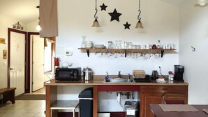 A compact kitchen with a microwave, toaster, sink, and coffee maker. There are star decorations on the wall and a sign that says 'All you need is love and a cabin.' - Serene Country Cabins 2 In the heart of Vermont (Hyde Park)