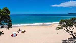 A beach with a tent and people near the water. - Perfect for the golfer or the family beach holiday (Tairua)