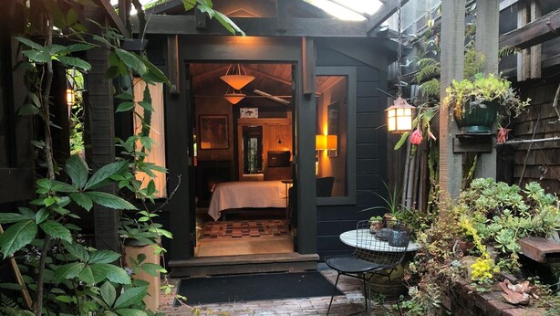 A cozy, dark-themed room with a bed, a small table, and a chair.