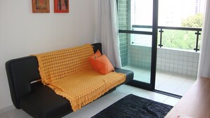 A room with a black sofa, a yellow blanket, and two paintings on the wall. - Modern apartment, beautifully decorated and furnished, with swimming pool and Wi-Fi. (Recife)