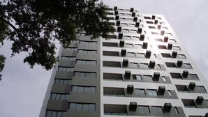 A high-rise building with multiple floors, each featuring a uniform design with balconies and air conditioning units. - Modern apartment, beautifully decorated and furnished, with swimming pool and Wi-Fi. (Recife)