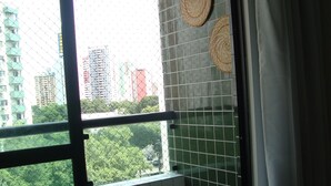 A balcony with a view of a cityscape, tiled walls, and a woven mat decoration. - Modern apartment, beautifully decorated and furnished, with swimming pool and Wi-Fi. (Recife)