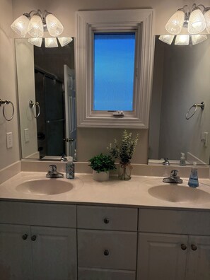 A bathroom with two sinks, a mirror, a window, and a shower. - Condo with AMAZING Ocean View! Labor Day Weekend is available and discounted ! (Ocean Isle Beach)
