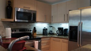 Eine moderne Küche mit Edelstahlgeräten, Holzschränken und einer Arbeitsplatte aus Granit.