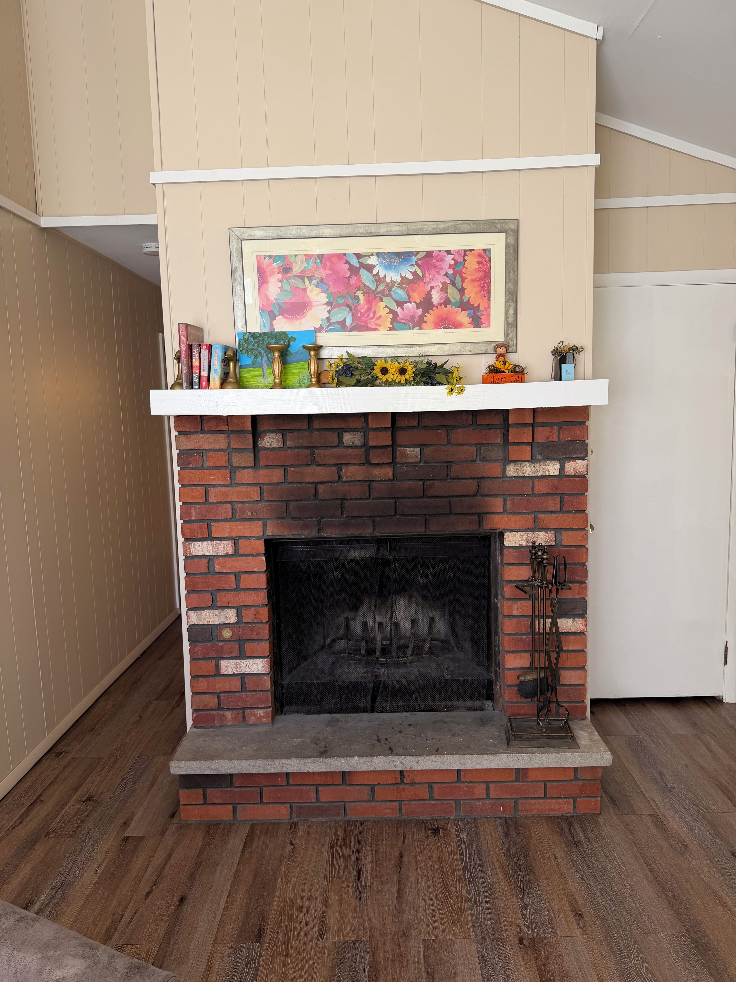 A fireplace with a brick surround, a mantel with decorative items, and a painting above it.