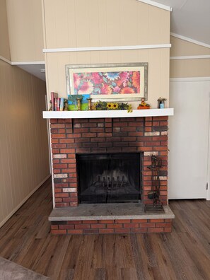 A fireplace with a brick surround, a mantel with decorative items, and a painting above it.