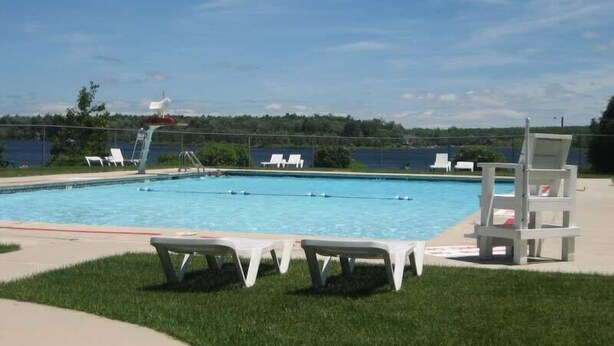 A swimming pool with a lifeguard chair, lounge chairs, and a clear view of the water.