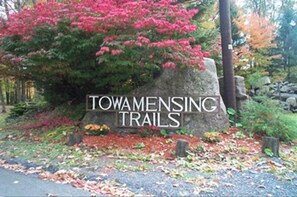 Skilt for Towamensing Trails med en stor sten og frodig vegetation omkring.