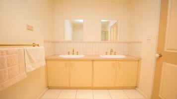 A bathroom with two sinks, a mirror, and a towel rack.