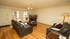 A living room with two leather sofas, a coffee table, a TV, and a lamp.
