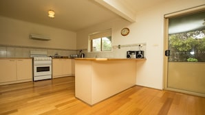 A kitchen with wooden cabinets, a central island, a built-in oven, and a window overlooking greenery.