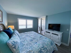 Un dormitorio con una cama, un televisor en una cómoda y una ventana con persianas.