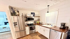 Une cuisine moderne dotée d’appareils électroménagers en acier inoxydable, de planchers en bois et offrant une vue sur l’extérieur.