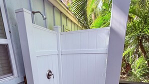 Une porte blanche avec une poignée argentée, une terrasse en bois et un tas de produits de nettoyage.
