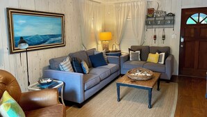 Un salon avec deux canapés, une table basse, une lampe et un tableau au mur.