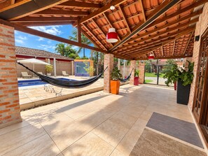 Eine Außenpatio mit einer Hängematte, einem Pool und Topfpflanzen.