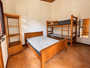 Ein Zimmer mit einem Etagenbett, einer Holzregaleinheit und einem Spiegel.