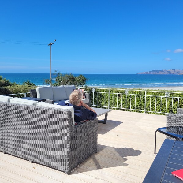 Une terrasse dotée de meubles en osier, d’une table et offrant une vue sur l’océan.
