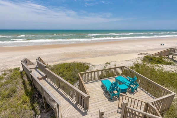 A wooden deck with a view of the beach and ocean.
