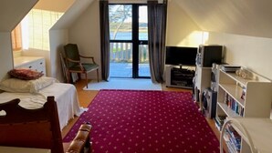 A bedroom with a bed, a desk, a chair, a TV, and a bookshelf. - Riverfront Cottage Waipu (Waipu)