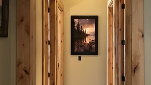 A hallway with wooden doors, a framed picture on the wall, and a carpeted floor.