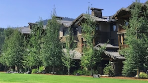 A multi-story lodge with stone and wood construction, surrounded by lush greenery and trees.
