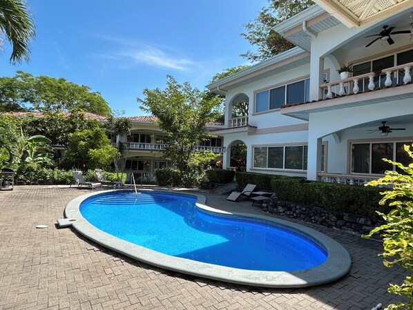 A two-story house with a swimming pool, outdoor furniture, and a covered patio area.