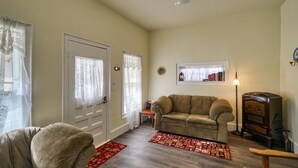 Ein Wohnzimmer mit einem beigen Sofa, einem roten Teppich mit Muster, einem Deckenventilator und einem Vintage-Radio.