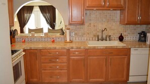 A kitchen with wooden cabinets, a tiled backsplash, a sink, and a stove. - Private 4BR Heated Pool & Spa Home • Pet Friendly • Near Beaches (Margate)