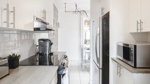 Une cuisine moderne avec des armoires blanches, des appareils en acier inoxydable et un îlot central.