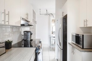 A modern kitchen with white cabinets, stainless steel appliances, and a central island.