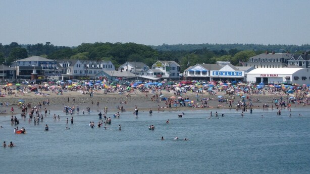Een strand met veel parasols en mensen.