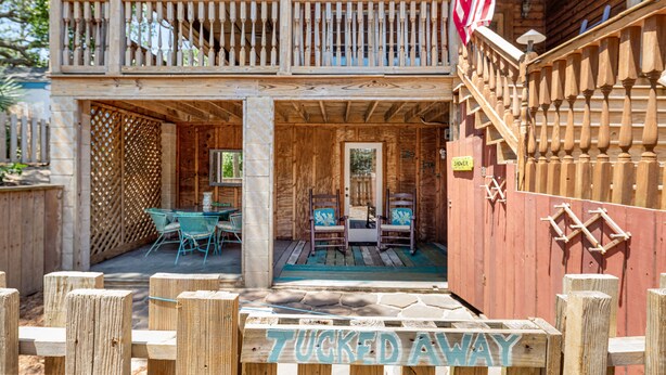 Une cabane en bois dotée d’un balcon, d’une véranda avec des chaises et d’une enseigne sur laquelle on peut lire : « À L’ABRI ».