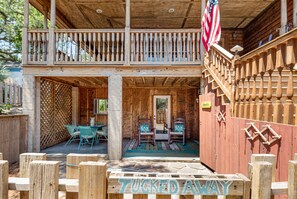 A wooden cabin with a balcony, a porch with chairs, and a sign that reads "TUCKED AWAY".