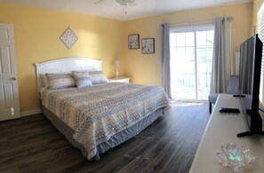 Quarto com cama, mesa de cabeceira, luminária e espelho.