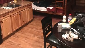 A cabin-style room with a bunk bed, wooden cabinets, a sink, and a dining table with chairs. - Cabin 7 (Garden City)