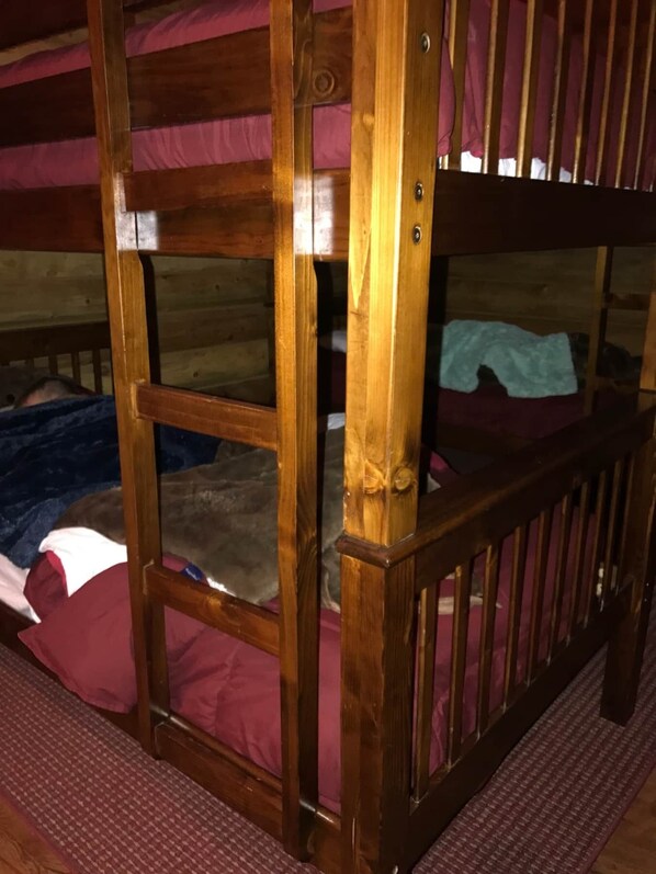 A wooden bunk bed with a metal guardrail.
