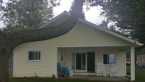 Une maison de plain-pied avec un porche couvert, une porte-fenêtre coulissante et un petit patio équipé de deux chaises.
