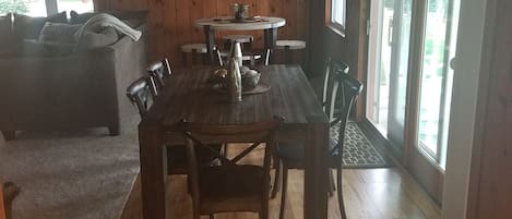 A wooden dining area with a table and chairs, a sofa, and a lamp.
