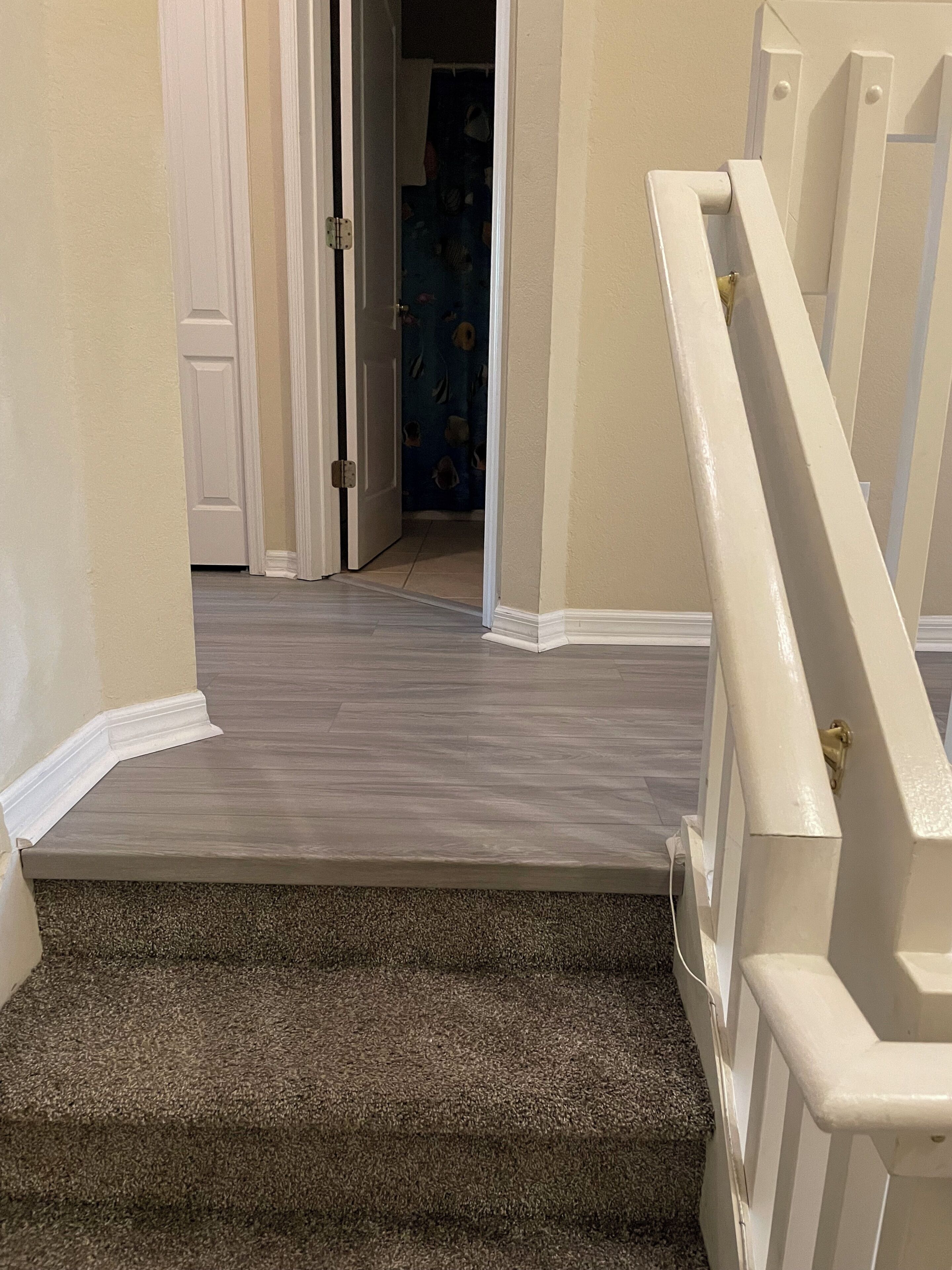 A staircase with a carpeted landing and a white railing.