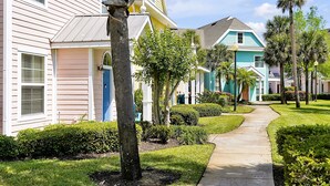 A row of pastel-colored houses with a well-maintained lawn and a pathway leading through.