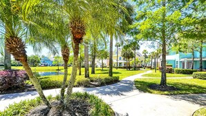 A pathway lined with palm trees and manicured lawns, leading to a building with a blue facade.