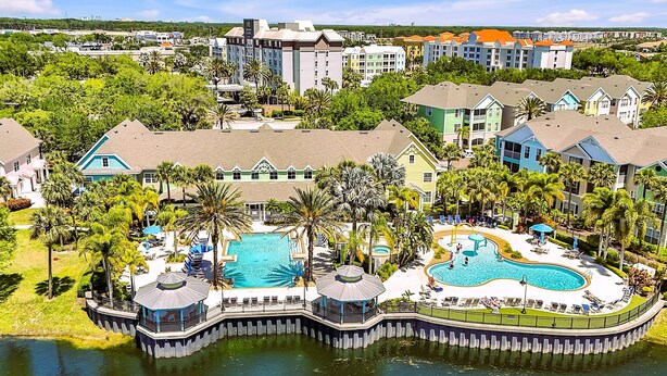 A resort with multiple swimming pools, a docked boat, and a view of the surrounding town.