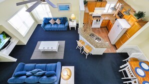 A spacious living area with a blue sofa, a coffee table, and a ceiling fan.