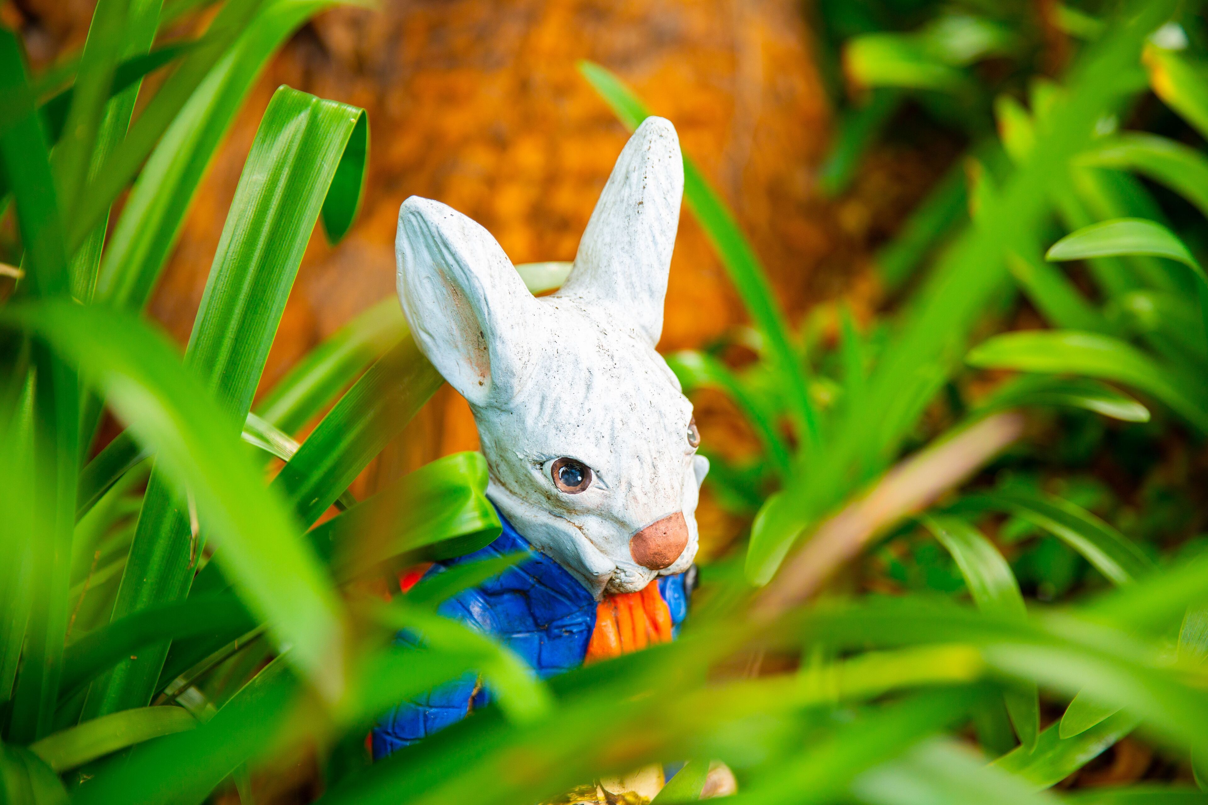 A rabbit figurine partially obscured by green foliage.